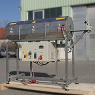 Four de transition en acier inoxydable avec un boîtier de commande en dessous et une partie supérieure à charnière pour chauffer une bande en acier sans fin